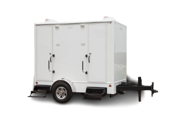 Compact two-stall restroom trailer with separate entrances and clean white exterior, suitable for events or worksites.