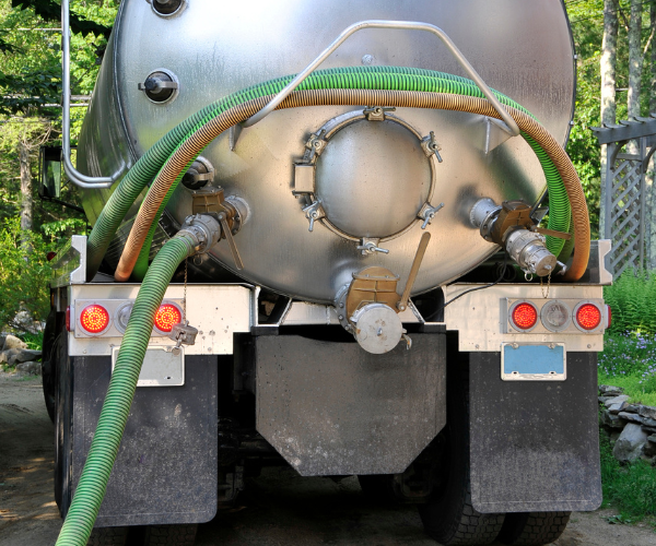 Septic system maintenance—technician accessing tank lid and riser for inspection.