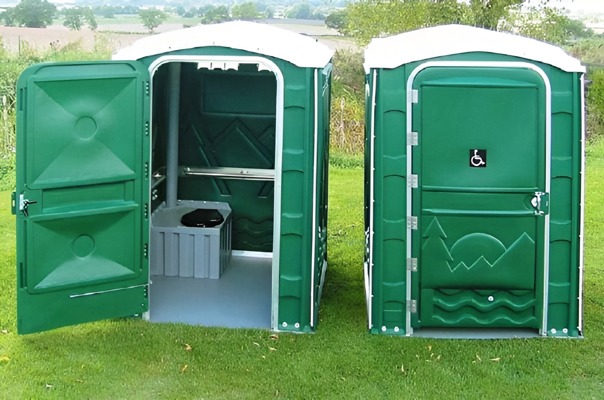 Spacious wheelchair-accessible portable restroom with flat-floor entry and side handrails, designed for easy mobility.