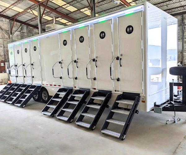 Spacious eight-stall restroom trailer with multiple doors and sleek construction, designed for large event setups.
