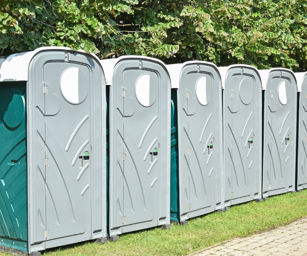 Standard portable toilet with molded seat, urinal, and hand sanitizer dispenser.